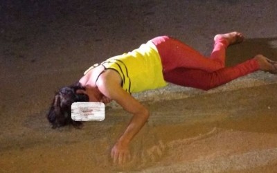 Homem com roupas de mulher deita em cruzamento e para o trânsito