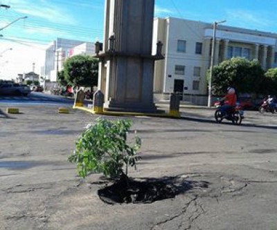 Moradora fotografa nova paisagem ao lado de Cartão Postal da cidade 
