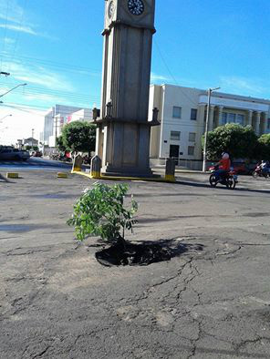 Moradora fotografa nova paisagem ao lado de Cartão Postal da cidade 